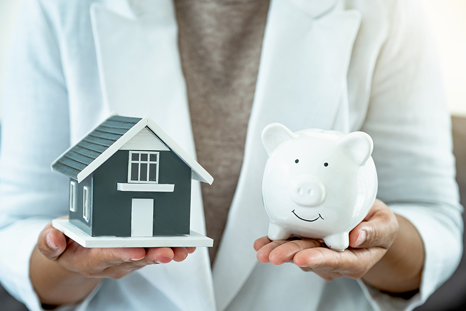 mani che sorreggono una casa e un salvadanaio